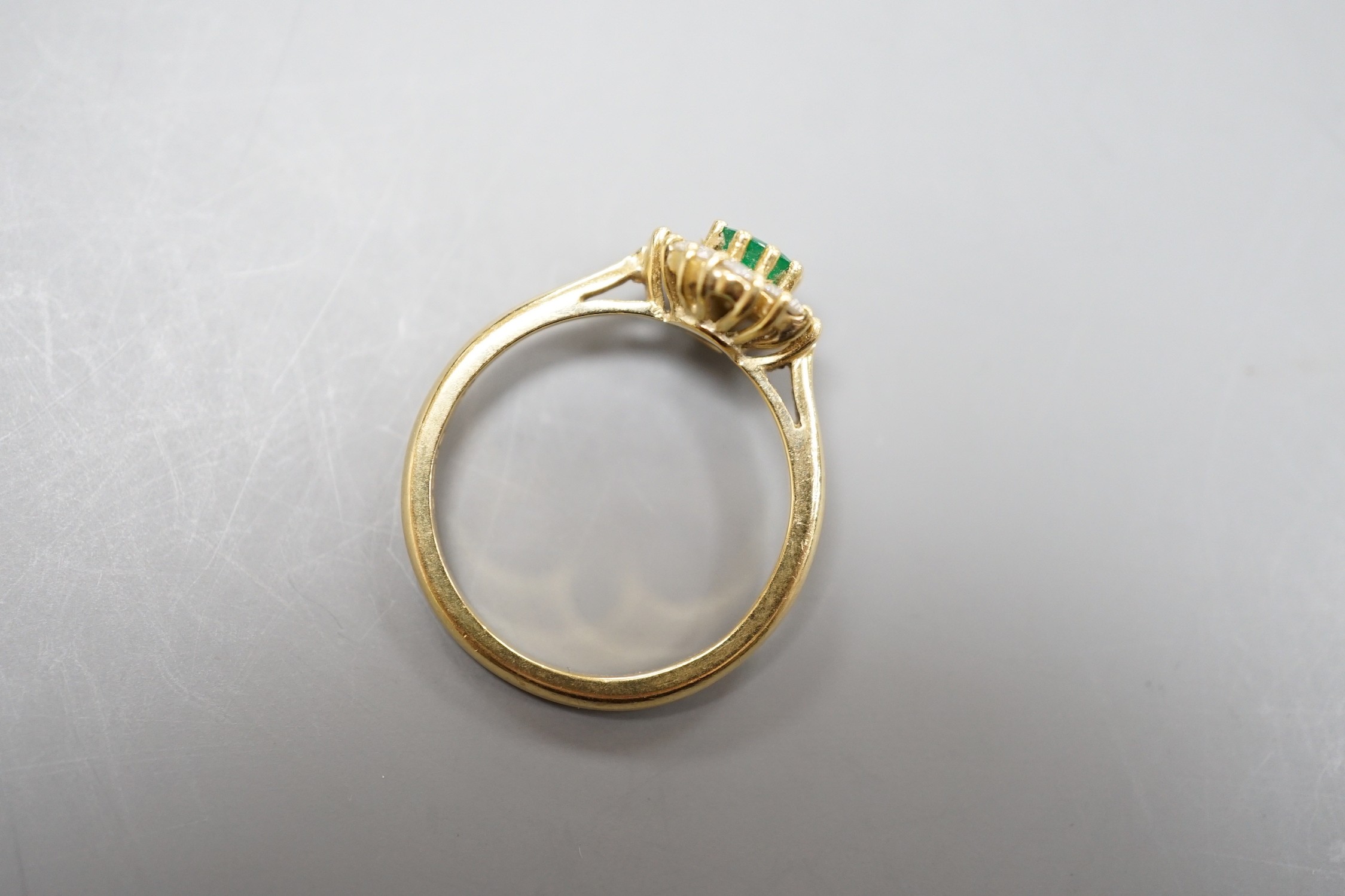 A modern 18ct gold, emerald and diamond set circular cluster ring, size M, gross weight 3 grams.